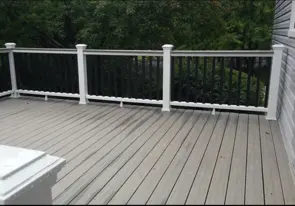 Finished deck with gray boards, white posts and black metal balusters
