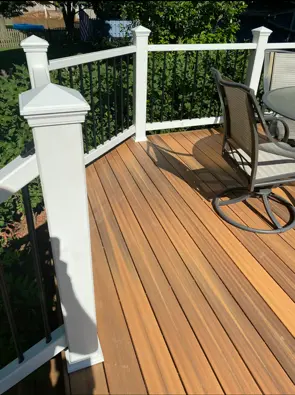 Wood-tone deck boards with white posts and black metal balusters