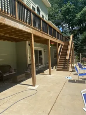 Elevated backyard deck with black balusters and stairs above a patio