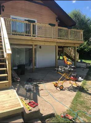 Raised wood deck under construction with tools on the patio below