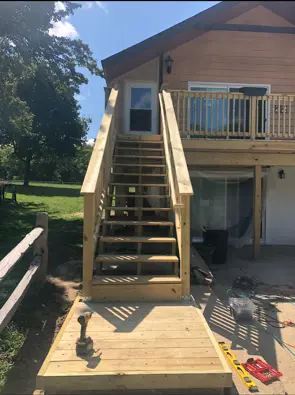 New wood stairs being built onto a raised backyard deck