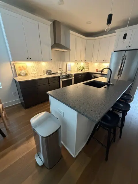 Two-tone kitchen with quartz island and black stools