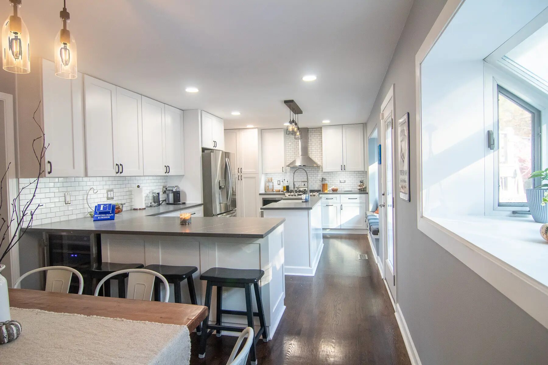 Bright completed kitchen with white cabinets, island seating, and stainless appliances