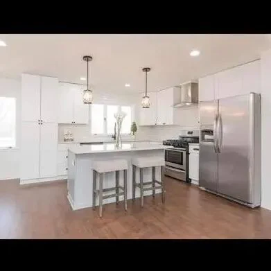 Bright completed kitchen with a compact island, white cabinetry, and wood flooring