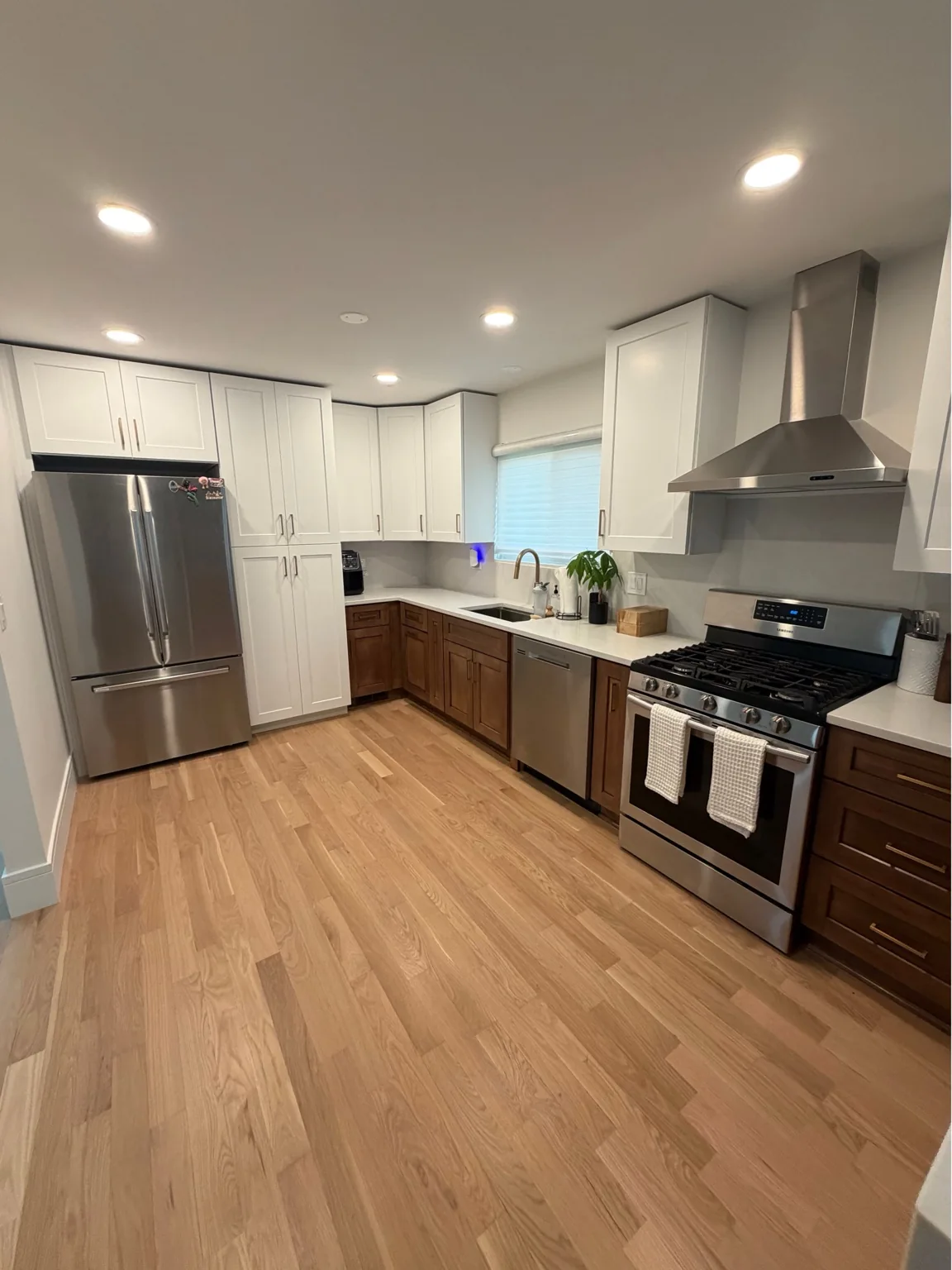 Two-tone kitchen with white shaker upper cabinets, wood base cabinets, stainless range and refrigerator